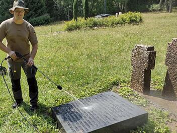 David Baer reinigt eine Grabplatte des Polenfriedhofs in Wildflecken. Foto: Thomas Helfrich