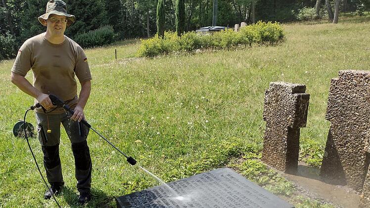 David Baer reinigt eine Grabplatte des Polenfriedhofs in Wildflecken. Foto: Thomas Helfrich