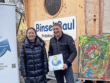 Allianzmanagerin Wenjun Zhang (v.l.), B&uuml;rgermeister Rainer Morper und Bernhard G&ouml;&szlig;mann-Schmitt vom Verein erLebenskunst freuen sich: Mit dem durch das Regionalbudget gef&ouml;rderten Anh&auml;nger bringt der Verein die Kunst in Schulen und Kinderg&auml;rten.