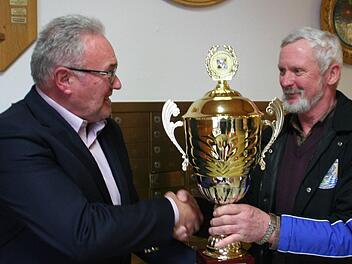 Pokal im Champions League Format für die siegreichen Schützen aus Reiterswiesen. Bürgermeister Thomas Leiner (links) gratuliert Burkard Faber.  Foto: Werner Vogel