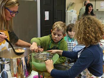 Mit der flotten Lotte wird der Brei zu Mus: Rektorin Barbara Hannweber schöpft und die Kinder dürfen abwechselnd rühren. Foto: Christiane Lehmann