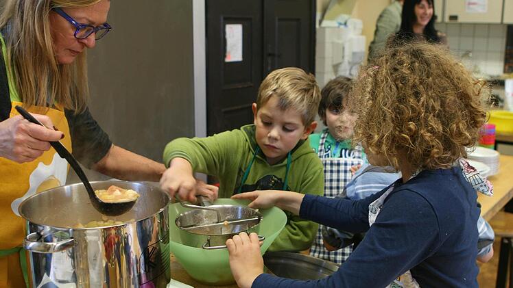 Mit der flotten Lotte wird der Brei zu Mus: Rektorin Barbara Hannweber schöpft und die Kinder dürfen abwechselnd rühren. Foto: Christiane Lehmann