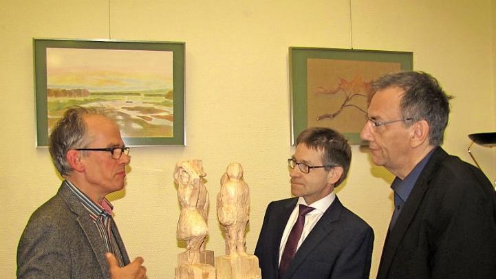 Diese Holzskulpturen sind im Kunstunterricht der neunten Jahrgangsstufe entstanden, ebenso die Bilder an der Wand. Von links: Kunsterzieher Peter Schmiedebach,  Schulleiter Hans-Joachim Döhner und Bürgermeister Thomas Nowak Foto: Martin Koch
