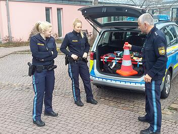 Polizeihauptkommissar Thomas Vöth (rechts) erklärt den beiden Auszubildenden Vanessa Wießner (links) und Katharina Wüscher (Mitte), welche Gegenstände zur Ausstattung eines Streifenfahrzeugs gehören. Die jungen Frauen absolvieren derzeit ein Berufspraktikum auf der Bad Brückenauer Dienststelle. Foto: Rolf Pralle