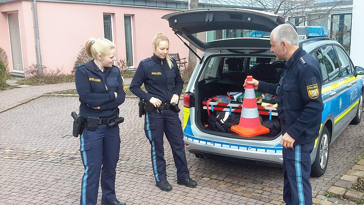 Polizeihauptkommissar Thomas Vöth (rechts) erklärt den beiden Auszubildenden Vanessa Wießner (links) und Katharina Wüscher (Mitte), welche Gegenstände zur Ausstattung eines Streifenfahrzeugs gehören. Die jungen Frauen absolvieren derzeit ein Berufspraktikum auf der Bad Brückenauer Dienststelle. Foto: Rolf Pralle
