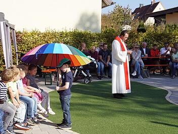 Ein großer Regenbogen-Schirm symbolisierte Gottes Schutz und Schirm, unter den Pfarrer Rusin den neuen Spielgarten und alle Kinder der Kindertagesstätte St. Magdalena in Ebelsbach stellte. Foto: Sabine Weinbeer