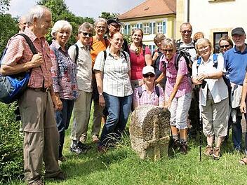 Hier posiert die Wandergruppe um Hildegard W&auml;chter (mit der Hand am Stein) am S&uuml;hnekreuz vor der Pfarrkirche Sankt Laurentius. Foto: Mario Deller