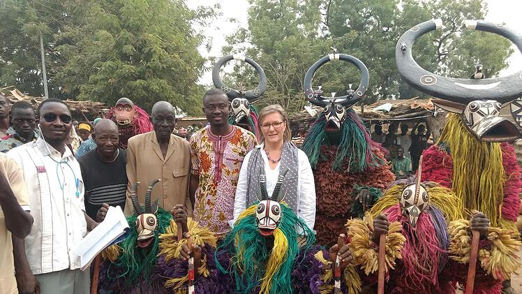 Kerstin Vaessen (Mitte) 2018 als stellvertretende Botschafterin der Bundesrepublik Deutschland bei der Einweihung des Projekts "Der Hammer mit zwei Köpfen" mit Burkinern mit traditionellen Masken  in Paradé in Burkina Faso.