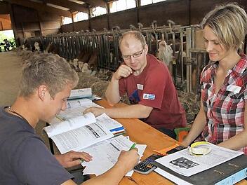 Martin Galster aus Leutenbach sitzt mit seinem Taschenrechner vor den Prüfern Agrarbetriebswirtin Susanne Weidner und Landwirtschaftsmeister Stefan Kraus im Kuhstall. Foto: Mathias Erlwein