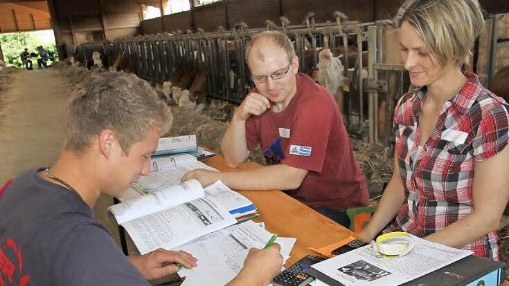 Martin Galster aus Leutenbach sitzt mit seinem Taschenrechner vor den Prüfern Agrarbetriebswirtin Susanne Weidner und Landwirtschaftsmeister Stefan Kraus im Kuhstall. Foto: Mathias Erlwein