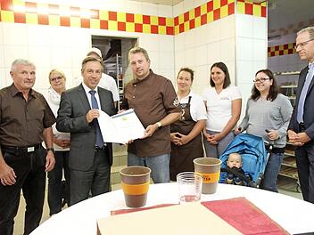 Landrat Alexander Tritthart überreicht die Urkunde, links Josef Polster und rechts Bürgermeister German Hacker, die Familie sowie Mitarbeiter der Bäckerei Foto: Richard Sänger
