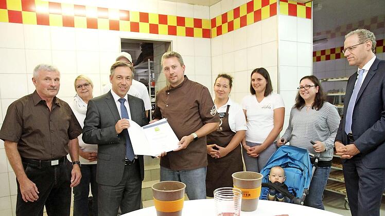 Landrat Alexander Tritthart überreicht die Urkunde, links Josef Polster und rechts Bürgermeister German Hacker, die Familie sowie Mitarbeiter der Bäckerei Foto: Richard Sänger