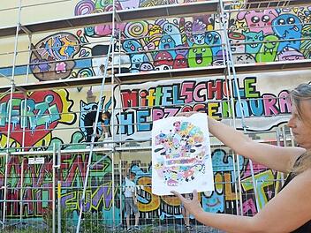 Im Juli 2017: Lehrerin Manuela Janisch präsentiert das Graffiti und seine Vorlage. Die Aktion weckte bei den Schülern Begeisterung. Auch wenn dieses Bild auf der Containerwand jetzt verloren geht, so hat Rektor Helmut Nicklas doch schon zwei neue Ideen.  Foto: Bernhard Panzer