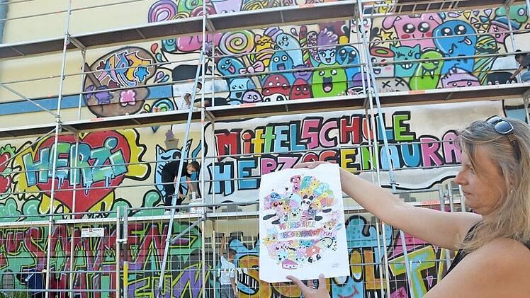 Im Juli 2017: Lehrerin Manuela Janisch präsentiert das Graffiti und seine Vorlage. Die Aktion weckte bei den Schülern Begeisterung. Auch wenn dieses Bild auf der Containerwand jetzt verloren geht, so hat Rektor Helmut Nicklas doch schon zwei neue Ideen.  Foto: Bernhard Panzer