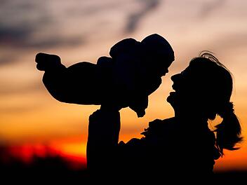 Eine Mutter hebt am 14.11.2010 vor dem Abendhimmel nahe dem brandenburgischen Sieversdorf (Oder-Spree) ihr Baby in die Luft. Frauen bekommen statistisch gesehen wieder so viele Kinder wie in den 1970er-Jahren. Die durchschnittliche Kinderzahl je Frau ist in Nordrhein-Westfalen auf 1,52 gestiegen, teilte das Statistische Landesamt am Dienstag auf Grundlage der Daten von 2015 mit. Foto: Patrick Pleul/dpa +++(c) dpa - Bildfunk+++