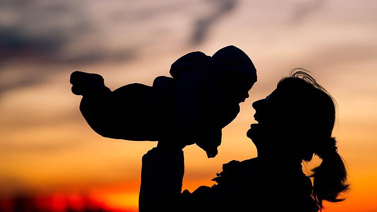 Eine Mutter hebt am 14.11.2010 vor dem Abendhimmel nahe dem brandenburgischen Sieversdorf (Oder-Spree) ihr Baby in die Luft. Frauen bekommen statistisch gesehen wieder so viele Kinder wie in den 1970er-Jahren. Die durchschnittliche Kinderzahl je Frau ist in Nordrhein-Westfalen auf 1,52 gestiegen, teilte das Statistische Landesamt am Dienstag auf Grundlage der Daten von 2015 mit. Foto: Patrick Pleul/dpa +++(c) dpa - Bildfunk+++