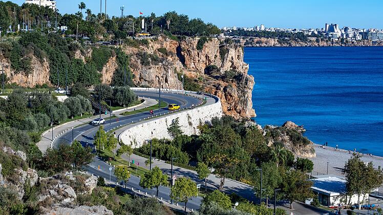 S-f&ouml;rmig gewundene Stra&szlig;e, die zum Konyaaltı-Strand hinunterf&uuml;hrt, mit Autos, felsigen Klippen und blauem Meer. Aufnahme von einem Aussichtspunkt aus. Antalya, T&uuml;rkei