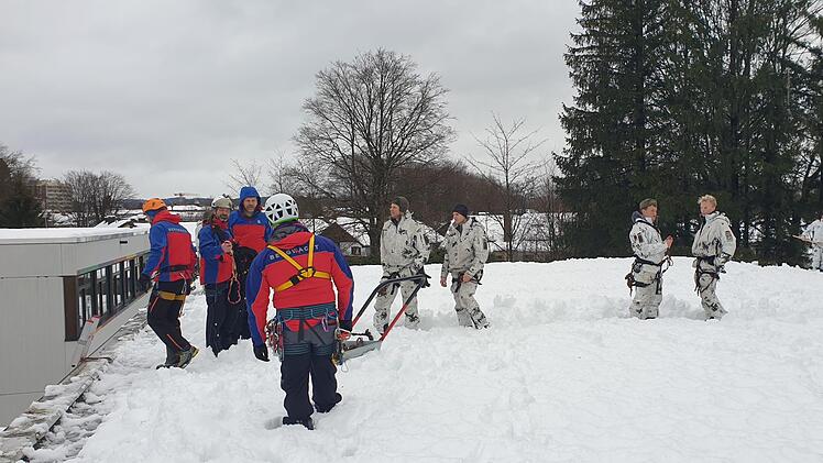 Gemeinsam mit einer Gruppe von Gebirgsjägern haben Helfer der Bergwachtbereitschaft Kulmbach-Obermain das Dach einer Schule vom Schnee befreit. Foto: Bergwacht