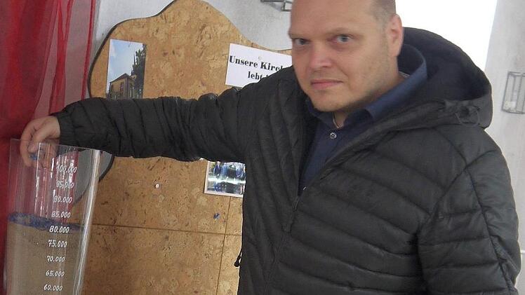 Pfarrer Michael Bergner mit dem Glas, das die Spendensumme für die Kirchenglocken anzeigt.Berthold Köhler