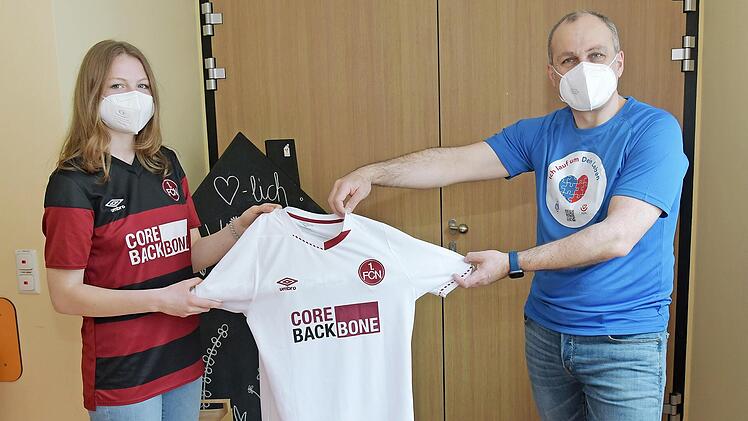 Die FCN-Spielerin Hanna Sauer überreicht Prof. Robert Cesnjevar ein FCN-Trikot. Im Gegenzug trägt sie für den guten Zweck das blaue T-Shirt der Aktion "Ich lauf um Dein Leben".
