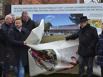 Enthüllung. Bürgermeister Martin Finzel zieht das Plakat beiseite, das bisher die Bautafel verdeckte, die über den Umbau zum Lehrschwimmbecken informiert.Rainer Lutz