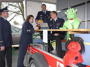 Kostenlos und interessant bei Aktionen mit Kindern und Jugendlichen: der neue Anhänger des Kreisfeuerwehrverbandes  Coburg zur Brandschutzerziehung. Stefan Beierlein und Claudia Ehrlinger lassen sich bei der Frühjahrskommandantentragung von Bernd Schultheiß und Detlef Schoder erklären, was alles auf dem Hänger zu finden ist - natürlich auch "Löschi", der Coburger Feuerwehrdrache. - Foto: Berthold Köhler