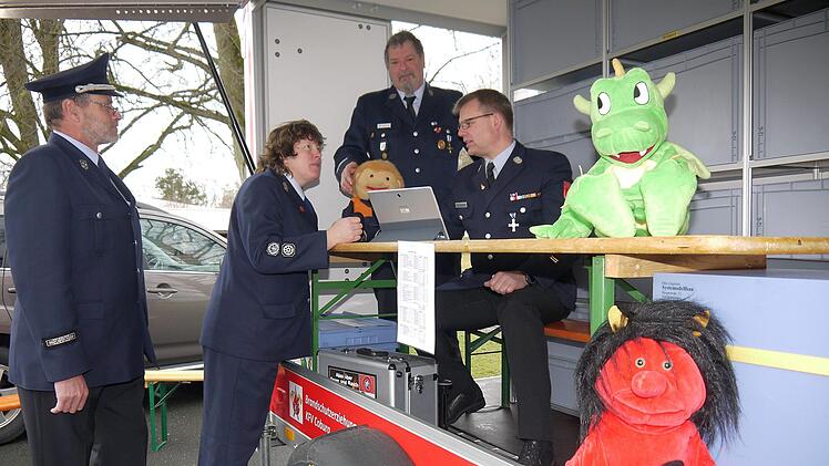 Kostenlos und interessant bei Aktionen mit Kindern und Jugendlichen: der neue Anhänger des Kreisfeuerwehrverbandes  Coburg zur Brandschutzerziehung. Stefan Beierlein und Claudia Ehrlinger lassen sich bei der Frühjahrskommandantentragung von Bernd Schultheiß und Detlef Schoder erklären, was alles auf dem Hänger zu finden ist - natürlich auch "Löschi", der Coburger Feuerwehrdrache. - Foto: Berthold Köhler