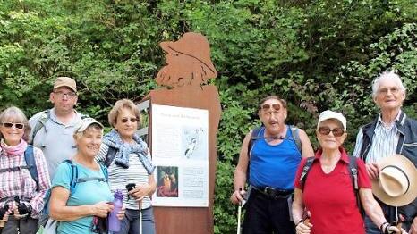 Bei der Wanderung gab es Zeitfenster in die Vergangenheit. Ein Teil der Wandergruppe vor einem Hinweisschild auf die Sagengestalt des Rh&ouml;n-Paulus. Foto: Hans-J&uuml;rgen Neumann