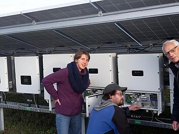 Der Elektriker Frank Gröbe zeigt den beiden Energiegenossen Johanna Düring und Günter Köth, wie die Anlage Sonnenlicht in Strom umwandelt und dann ins Netz weiter transportiert.  Foto: Heike Beudert