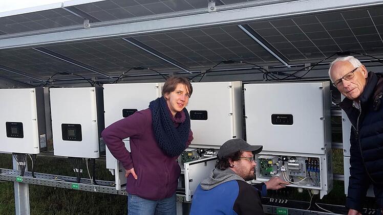 Der Elektriker Frank Gröbe zeigt den beiden Energiegenossen Johanna Düring und Günter Köth, wie die Anlage Sonnenlicht in Strom umwandelt und dann ins Netz weiter transportiert.  Foto: Heike Beudert