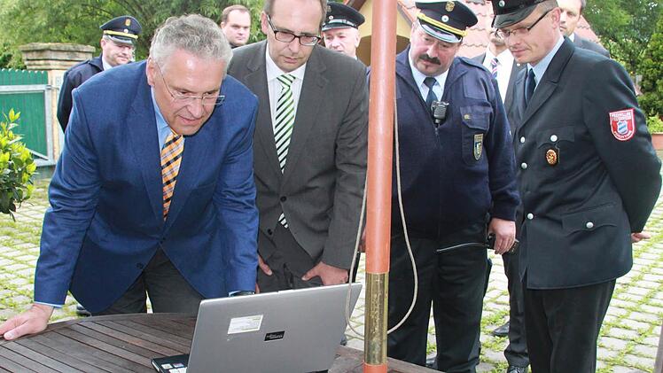 Minister Joachim Herrmann, Landrat Christian Meißner, KBI Gerhard Elflein und Bernhardt Gehringer von der Prächtinger Feuerwehr (von links) sehen sich den Tagesschau-Beitrag über die Auswirkungen des Unwetters in Prächting an.