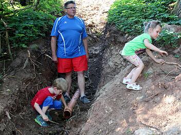 Die wiederentdeckte Heiligenquelle in der Gemündaer Flur, die Hermann Gossenberger hier seinen Enkeln Elena und Finn zeigt, kennen bisher nur wenige Eingeweihte. Noch rinnt das Wasser aus einem schmucklosen Plastikrohr. Auf Wunsch der "Stiftung 1150 Jahre Dorfgemeinschaft Gemünda" soll sich beides durch einen Gestaltungswettbewerb bald ändern.Foto: Bettina Knauth