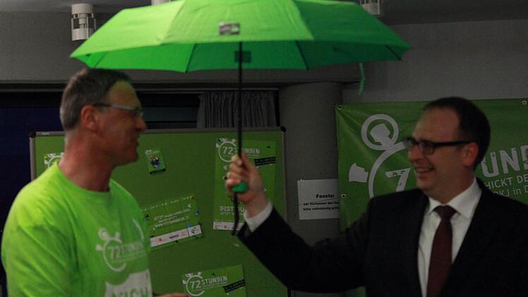 Pfarrer Georg Birkel übergab Landrat Christian Meißner einen grünen Regenschirm als Zeichen der Schirmherrschaft über die 72-Stunden-Aktion des BDKJ im Landkreis Lichtenfels. Foto: Manuel Stark