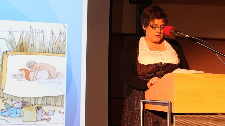Heike Kunzelmann vor einer auf Leinwand projizierten Kinderbuchseite, die sie für Kinder als ungeeignet empfand.
