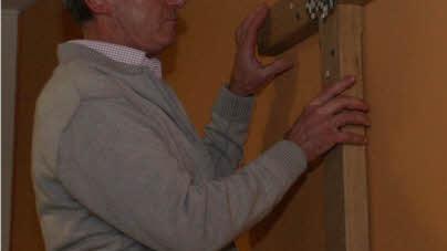Georg Jordan hängt das neue Kreuz im Gemeindesaal auf.