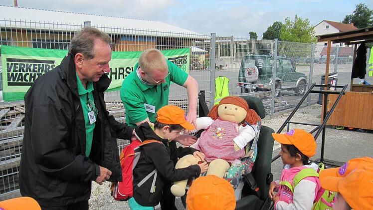 Walter Mackert (li) und Holger Reinlein von der Verkehrswacht üben mit den Vorschulkindern das richtige Anschnallen mit dem Dummy Klara