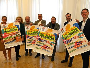 Sechs Personen präsentieren bunte Plakate für das Familienfest in Bamberg 2024, das 20 Jahre Familienbeirat mit Workshops, Bühnenauftritten und Tombola feiert.