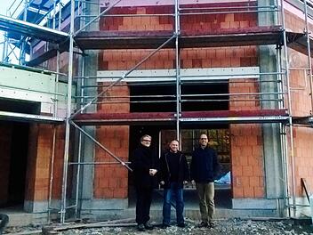 Pfarrer Florian Judmann (von links), Architekt Michael Kirchner und Bürgermeister Gerd Kleinhenz stehen vor dem Rohbau der neuen Kapelle. Foto: Sebastian Schmitt-Mathea