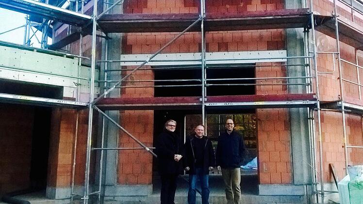 Pfarrer Florian Judmann (von links), Architekt Michael Kirchner und Bürgermeister Gerd Kleinhenz stehen vor dem Rohbau der neuen Kapelle. Foto: Sebastian Schmitt-Mathea