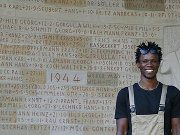 Jamba strahlt vor dem abgeschlossenen Werk. An der Kriegergedächtniskapelle in Eltmann hat er gemeinsam mit einem weiteren Flüchtling die gesamten Inschriften neu ausgemalt.  Foto: Sabine Weinbeer