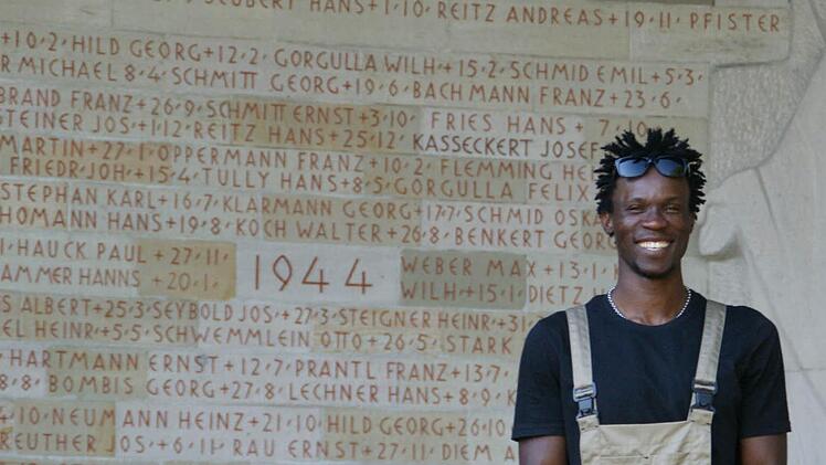 Jamba strahlt vor dem abgeschlossenen Werk. An der Kriegergedächtniskapelle in Eltmann hat er gemeinsam mit einem weiteren Flüchtling die gesamten Inschriften neu ausgemalt.  Foto: Sabine Weinbeer