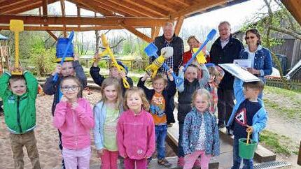Der Sandkasten der Trebgaster KiTa wird zum Schutz vor Schmutz mit einer Abdeckung versehen. Dafür sorgen Präsidentin Rosi Müller und Bernt Pingel von Kiwanis (hinten rechts und links). Pfarrer Peter Ahrens und Leiterin Jacqueline Ramming freuen sich über die Spende. Foto: Hübner
