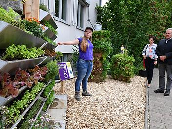 Sarah Helmert erklärt das vertikale System (l.) und den Pflanzturm (r.) im Demonstrationsgarten. Foto: Ronald Rinklef