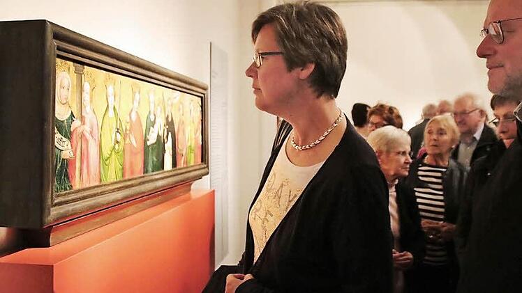 Gabi Borst und Stadtpfarrer Pater Markus Reis betrachten die Predella des sogenannten Münnerstädter Marientod-Altars. Das Gemälde ist derzeit als Leihgabe im Germanischen Nationalmuseum zu sehen und fand bei der Ausstellungseröffnung viel Beachtung. Foto: Heike Beudert
