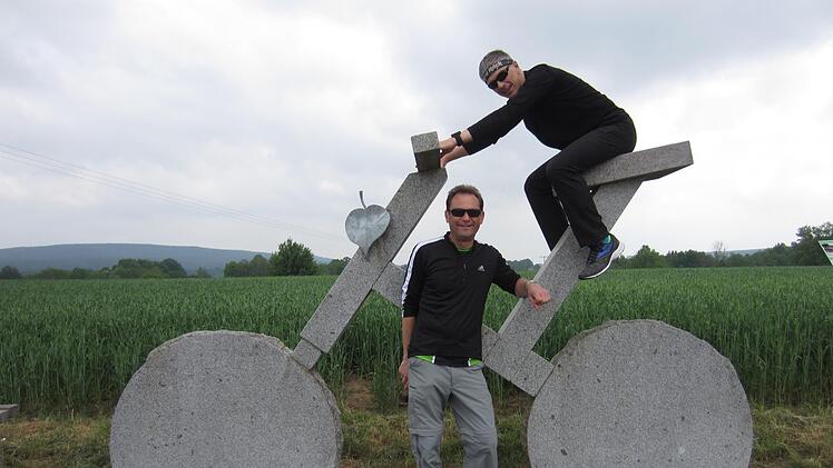 Jochen Brosig (oben) und Harald Rist testen das steinerne Fahrrad, eines der beliebtesten Fotomotive entlang des Main-Radwegs. privat