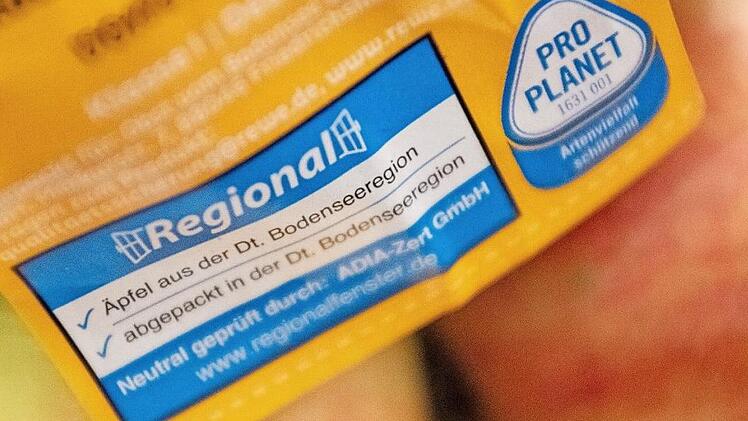 Das Logo "Regionalfenster" in einer Küche auf einer Packung mit Äpfeln. Die Verbraucherzentralen fordern mehr Klarheit und genauere Vorgaben bei der Werbung mit regionalen Lebensmitteln. Foto: Lino Mirgeler, dpa