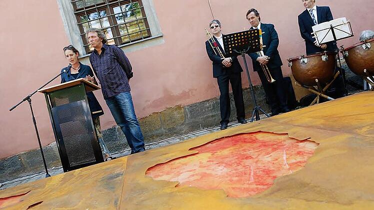 Das Künstlerehepaar Miriam Giessler und Hubert Sandmann bei ihrer Rede. Rechts Mitglieder der Bamberger Symphoniker Fotos: Matthias Hoch