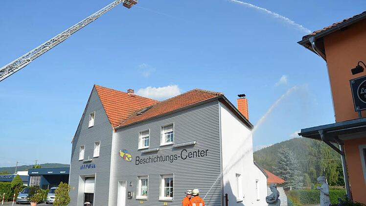 Mit Wasser über die Drehleiter der Kronacher Feuerwehr wurde ein Nachbargebäude vom Flammenübergriff geschützt. Foto: Karl-Heinz Hofmann