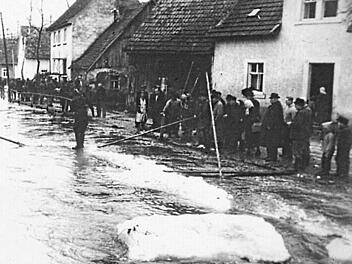 Die Menschen stehen hilflos in der Wehrstraße und hoffen auf Besserung der Wetterlage. Repros: Sesselmann
