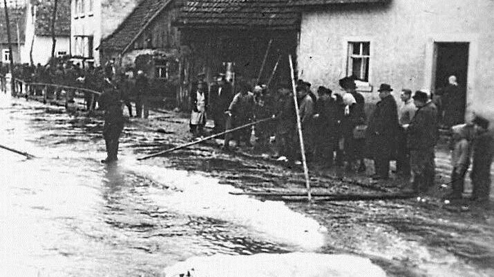 Die Menschen stehen hilflos in der Wehrstraße und hoffen auf Besserung der Wetterlage. Repros: Sesselmann